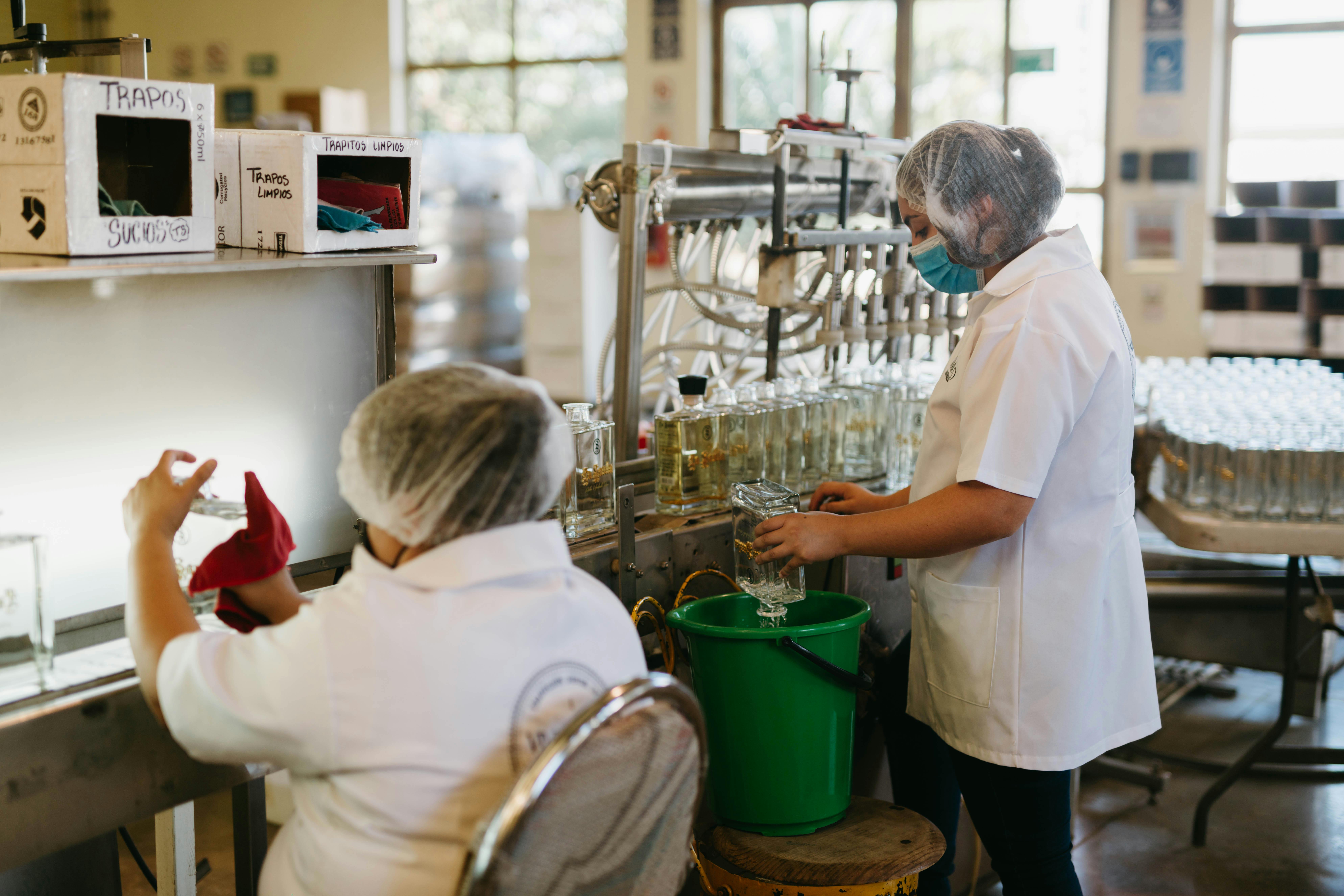 Workers in a tequila factory bottling and cleaning with precision. Industrial process.