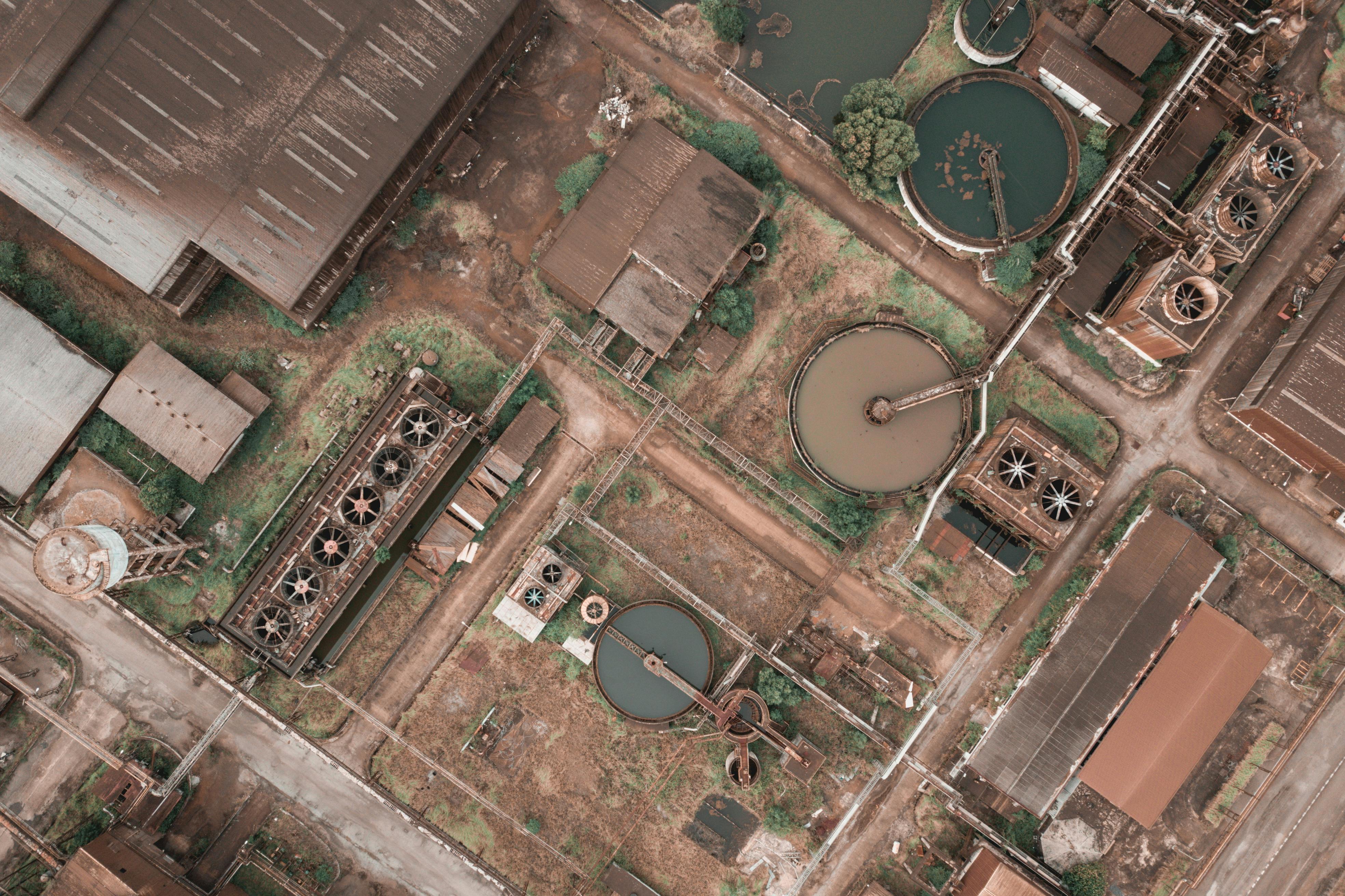 Drone view of shabby factory with round settling tanks with mechanical means removing solids in water treatment plant